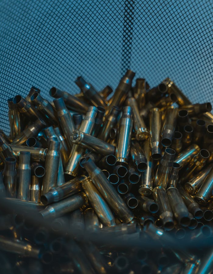 A collection of metallic bullet casings in a mesh container, reflecting industrial ambiance.
